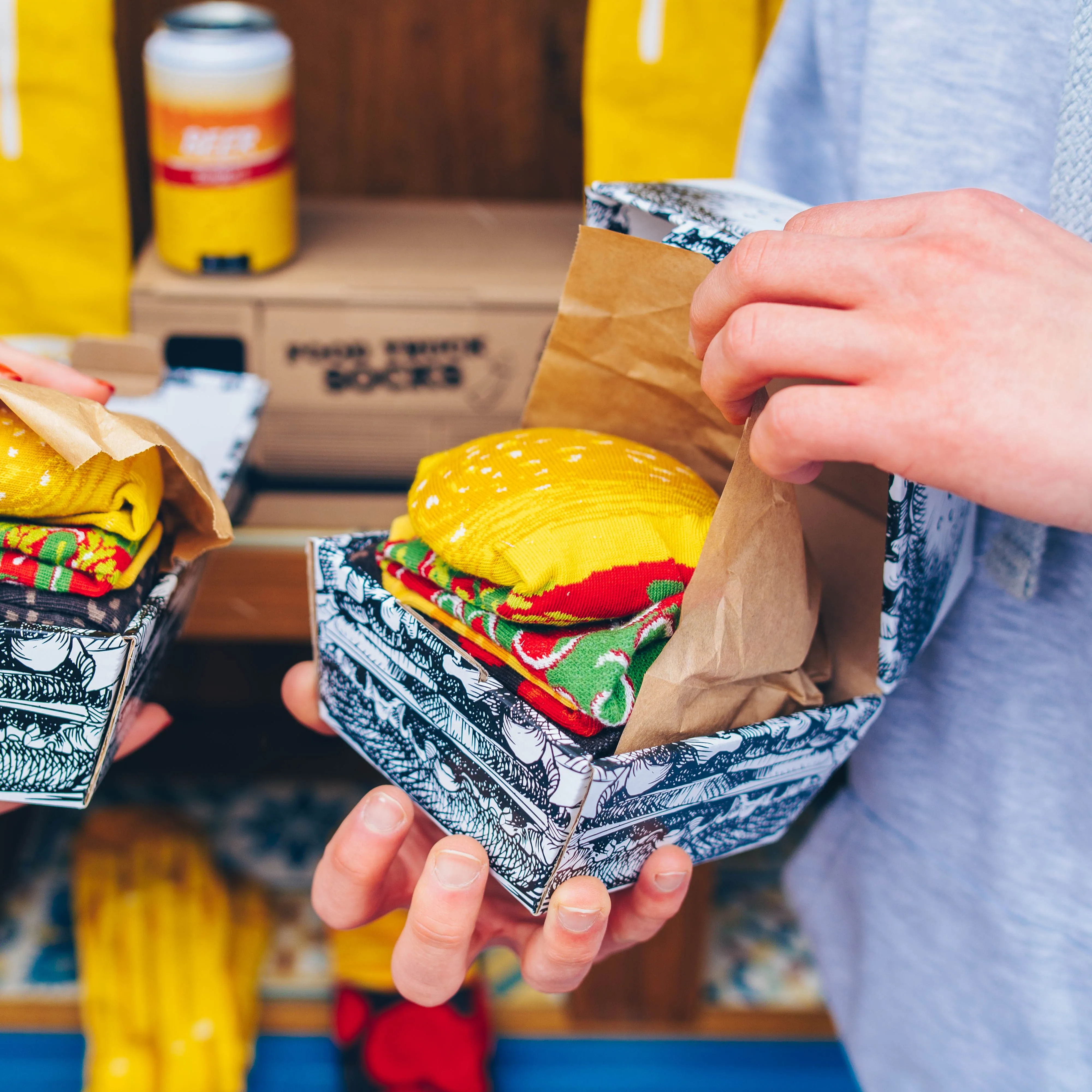 Ein Mann hält Burger-Socken von Rainbow Socks in seinen Händen.