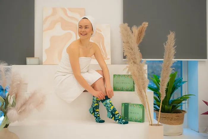 Lächelnde Frau beim Anprobieren von Socken für die Selbstpflege
